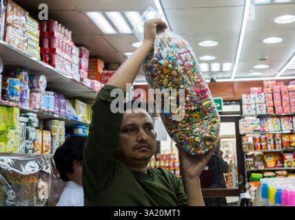 Ramadan 2025 ÒGarangaoÓ Vorbereitung der Feier in Doha trägt Ein Händler eine Tüte Garangao-Gegenstände auf dem Souq Waqif Traditional Market, um das bevorstehende Garangao-Festival während des heiligen Fastenmonats der Muslime am 10. März 2025 in Doha, Katar, vorzubereiten. Das Festival, das hauptsächlich in den Golfstaaten gefeiert wird, bietet Süßigkeiten, Nüsse, Geschenke und Spiele als Grundpfeiler der uralten Golftradition, bekannt als Garangao, das nach dem Abendgebet am 14. Tag des Ramadan DOHA Qatar gefeiert wird Copyright: XNOUSHADx Stockfoto