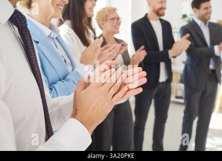 Applaudieren Sie Mitarbeitern, die im Büro fröhlich die Hände klatschen, die Mitarbeiter jubeln, stehen in einem modernen Büro Stockfoto