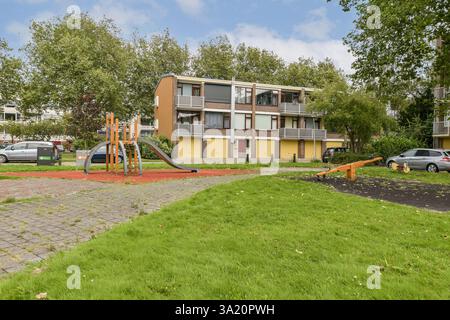 Ein lebendiger, moderner Spielplatz fügt sich in ein Wohngebiet ein und bietet verspielte Strukturen in grüner Umgebung, die das Engagement und den Genuss der Gemeinschaft fördern. Stockfoto