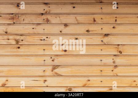Holzpaneele bilden eine durchgehende strukturierte Oberfläche, die natürliche Körnung, Knoten und eine rustikale Ästhetik unter Licht zeigt. Ideal für Hintergrundanwendungen Stockfoto