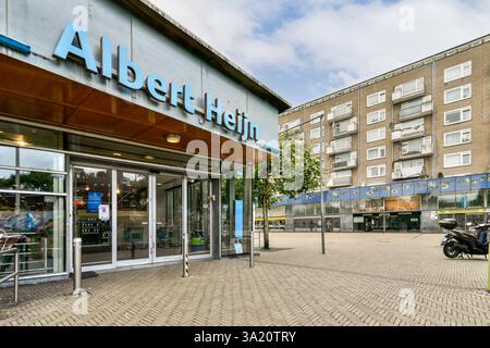 Eine pulsierende Stadtlandschaft mit einem Supermarkt von Albert Heijn inmitten von Wohngebäuden, die das tägliche Leben in der Stadt einfangen. Stockfoto