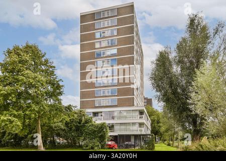 Ein modernes, mehrstöckiges Wohngebäude befindet sich inmitten üppiger Grünanlagen und bietet eine Mischung aus Natur und Architektur. Stockfoto