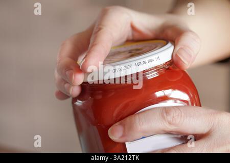 Öffnen Sie ein festsitzendes Gefäß. Frau, die Glas mit Tomaten aufmacht Stockfoto