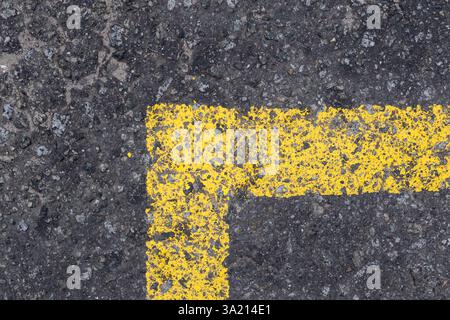 Diese Nahaufnahme zeigt eine verwitterte gelbe Parklinie auf strukturiertem Asphalt, die den Kontrast zwischen der leuchtenden Farbe und dem rauen Bürgersteig unterstreicht und ein optisch ansprechendes Detail schafft Stockfoto