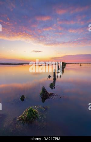 Ein wunderschöner Sonnenuntergang über dem Wattenmeer mit einem Himmel voller Abendrot. Die Farben spiegeln sich auf dem Wasser des Meeres wider. - Meeresbild Stockfoto