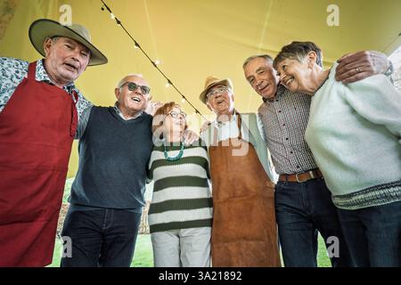Eine Gruppe glücklicher Seniorenfreunde, die bei einer Party im Freien lächeln und Freundschaft und soziales Leben während des Ruhestands genießen. Stockfoto