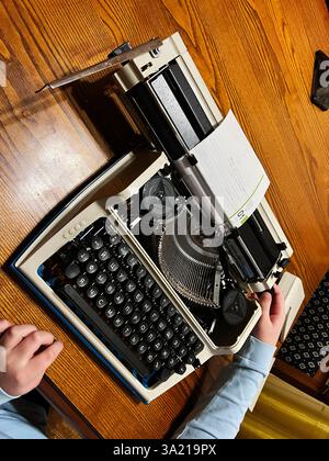 Die Hände liegen auf einer Vintage-Schreibmaschine auf einer hölzernen Schreibtischoberfläche Stockfoto
