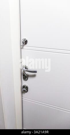 Weiße Tür mit Metallgriff und Schlössern als Teil der Innenarchitektur Stockfoto