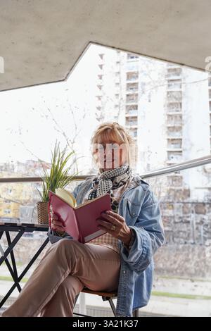 Eine Seniorin liest ein Buch auf ihrer Terrasse. Genießen Sie sant jordi Stockfoto