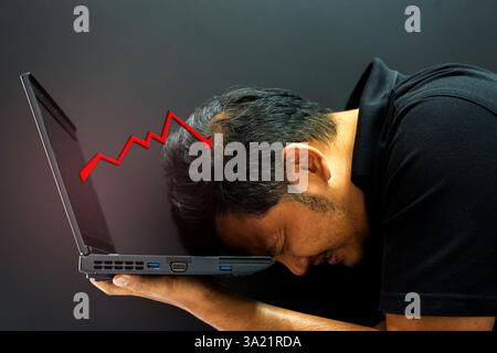 Asiatischer Mann der 40er Jahre hält Computer-Laptop mit Stress in der Börsengrafik Geschäft fallen nach unten Konzept Stockfoto