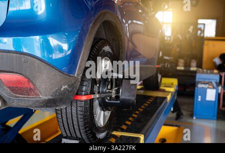 Radausrichtergeräte greifen den Reifen des Autorads in der Kfz-Werkstatt. Automatische Spureinstellung in der Werkstatt der Servicestation. Auto-Radwaage. Stockfoto