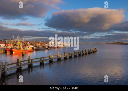 Sonnenuntergang über dem kleinen Dorf Zoutkamp in den Niederlanden mit Reflexionen des Himmels im Kanal und Fischereifahrzeugen im Hintergrund. Stockfoto