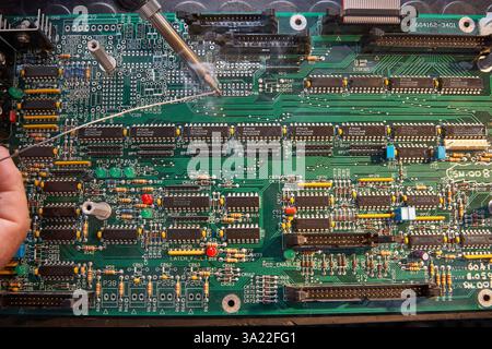 Elektronik-Reparaturszene mit Leiterplatte und Lötprozess im Detail Stockfoto