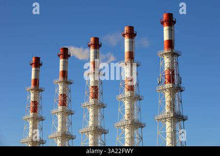 Rauchende Pfeifen auf klarem Himmel Hintergrund. Konzept der Dampfanlage, Luftverschmutzung, Heizsaison oder Fabrikschornstein Stockfoto
