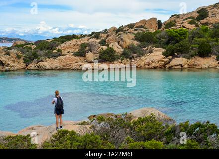 Eine Touristenfrau, die vor dem azurblauen Wasser der Insel Caprera, Sardinien, Italien, steht Stockfoto
