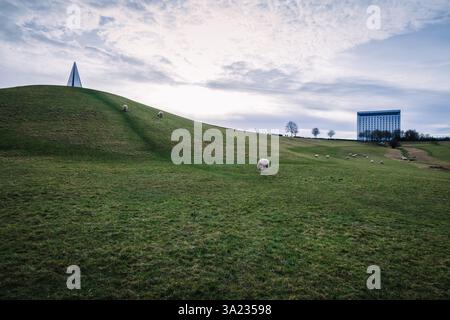 Eine ruhige Winterlandschaft des Campbell Park in Milton Keynes, mit einem kleinen Denkmal auf einem kurvigen Hügel, Schafen auf einem grünen Hang und einer Vielzahl von Tieren Stockfoto