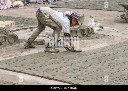 Fes, Marokko: Marokkanischer Handwerker, der Fliesen mit Zement herstellt. Er füllt die Form mit einer Mischung aus Zement, Sand und Pigment. Stockfoto