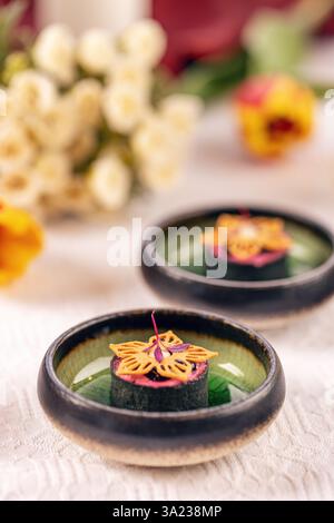 Gourmet-Vorspeisen werden auf kleinen Tellern mit Blumen im Hintergrund serviert Stockfoto