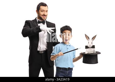 Ein Zauberer und ein Kind, der einen Trick mit einem Hut und einem Kaninchen auf weißem Hintergrund vorführt Stockfoto