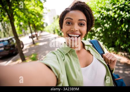 Eine junge Frau macht ein fröhliches Selfie an einem sonnigen Tag im Park Stockfoto