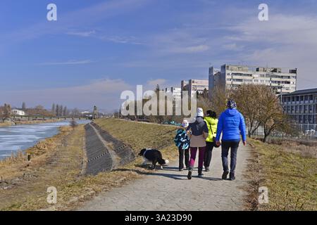 Die ganze Familie schlendert an einem Wintermorgen am Ufer des Flusses Mures entlang Stockfoto