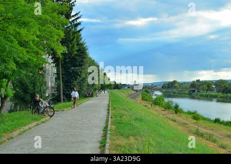An einem Sommernachmittag schlendern Menschen am Ufer des Flusses Mures entlang Stockfoto