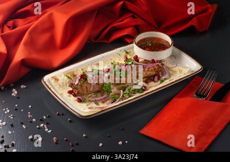 Gegrillter Lula-Kebab auf Spießen mit Gewürzen im Teller auf dunklem Hintergrund. Georgianisches Restaurant. Restaurantmenü. Stockfoto