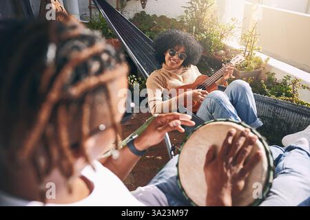 Freunde, entspannen und Instrumente für Spaß spielen, Outdoor und Musiker unterstützen beim Üben. Bongo, Musik-Hobby und gemeinsam am Wochenende für chillen Stockfoto