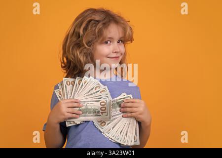 Das Kind hat viele hundert Dollar isoliert auf gelbem Hintergrund. Stockfoto