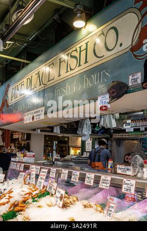 Ein Mitarbeiter von Pike Place Fish Co. Steht hinter einer Theke mit frischen Meeresfrüchten und steht bereit, Kunden zu bedienen. Stockfoto