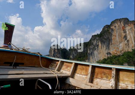 Blick von einem traditionellen hölzernen Boot auf die hoch aufragenden Kalksteinklippen von Railay Stockfoto