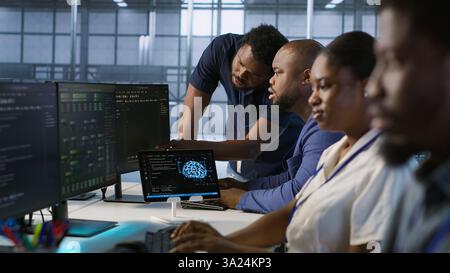 Teamleiter im Serverraum unterrichtet den Praktikanten bei der Entwicklung von Disaster Recovery-Plänen, die minimale Ausfallzeiten gewährleisten. IT-Spezialist für Rechenzentren, der Mitarbeiter bei der Leistungsüberwachung unterstützt, Kamera A Stockfoto