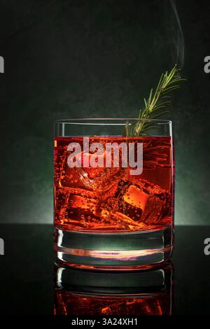 Cranberry-Gin-Cocktail mit einem Zweig rauchigen Rosmarin Stockfoto