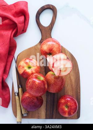 Ganze und geschnittene rote Äpfel auf einem Holzbrett Stockfoto