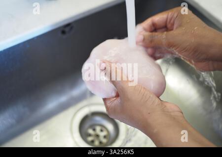 Hände waschen rohes Hühnchen vor dem Kochen in einer Küchenspüle Stockfoto