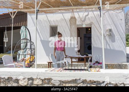 Telendos Griechenland - 29. August 2024; Küstenszene auf der Insel Telendos mit malerischen traditionellen Fischerbooten und Inselhügeln im Hintergrund; Stockfoto