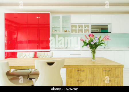 Moderne Küche mit roten Schränken, zwei Waschbecken, Gasherd, Einbauschränken mit roten Schranktüren. Stockfoto