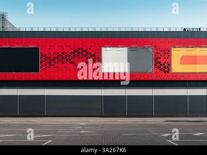 Leere Straße und Parkplatz in der Nähe einer Mauer des Einkaufszentrums. Werbespots an den Gebäudewänden. Stockfoto