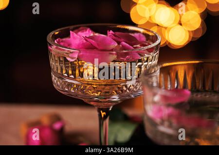 Nahaufnahme des Champagnerglases mit Rosenblüten und Bokeh-Lichtern Stockfoto