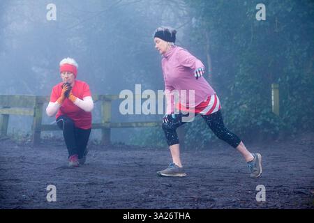 Zwei ältere Frauen in sportlicher Kleidung trainieren an einem nebeligen Tag im Freien. Sale Water Park, Manchester, Großbritannien Stockfoto
