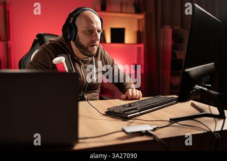 Gamer-Streamer spielen Online-Spiele auf dem PC in dunklen Räumen. Fokussierter Blick auf den Bildschirm voll im Online-Spiel. E-Sport Games und Internet Championship Stockfoto