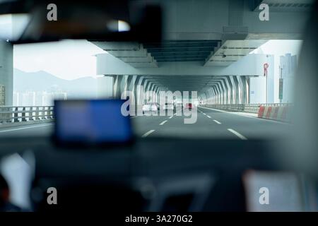 Blick aus dem Inneren eines Autos, das auf einer Autobahn durch einen modernen Betontunnel unter einem bewölkten Himmel fährt. Busan, Korea Stockfoto