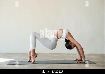 Seitenansicht, stehende Hände und Beine. Fitness-Frau ist drinnen in weißen Kleidern. Stockfoto