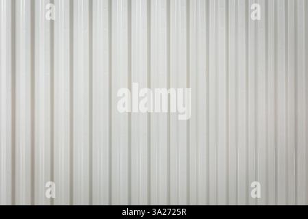 Weißer Metallheizkörper mit modernem minimalistischem Design in einem hellen Innenraum. Heizelement, Nahtstruktur mit vertikalen Linien. Wärme A Stockfoto