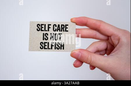 Selbstfürsorge ist keine egoistische Botschaft, die auf einer Karte in der Hand geschrieben wird. Konzeptionelle Selbstfürsorge ist kein egoistisches Symbol. Kopierbereich. Stockfoto
