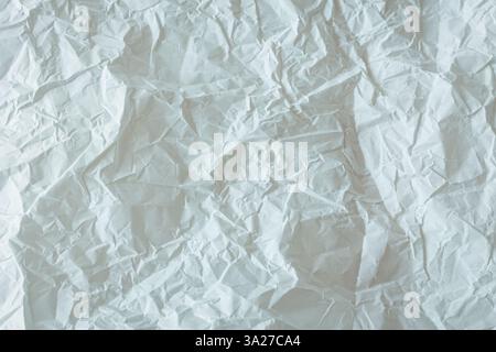 Nahaufnahme von zerknittertem weißem Papier mit weicher natürlicher Beleuchtung. Ideal als Hintergrund für Design-, Scrapbooking- oder digitale Kunstprojekte. Hohe Auflösung Stockfoto
