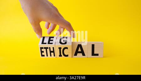 Ethisches und rechtliches Symbol. Geschäftsmann dreht Holzwürfel und ändert das Wort ethisch in legal. Schöner gelber Hintergrund. Geschäftliche und ethische Aspekte Stockfoto