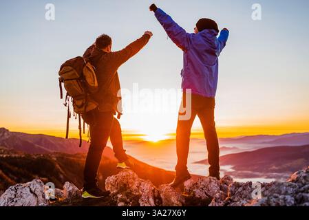 Zwei glückliche Freunde Wanderer stehen mit den Armen oben auf dem Gipfel während der Wanderung, Abenteuer Reise. Stockfoto