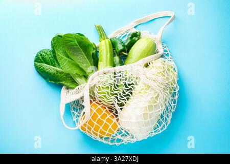 Netztasche mit Produkten auf hellblauem Hintergrund, Draufsicht. Umweltfreundlicher Lebensstil Stockfoto
