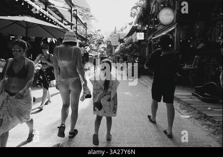 Moderne Familienbummeln durch die belebten Straßen von Railay in Schwarz-weiß Stockfoto